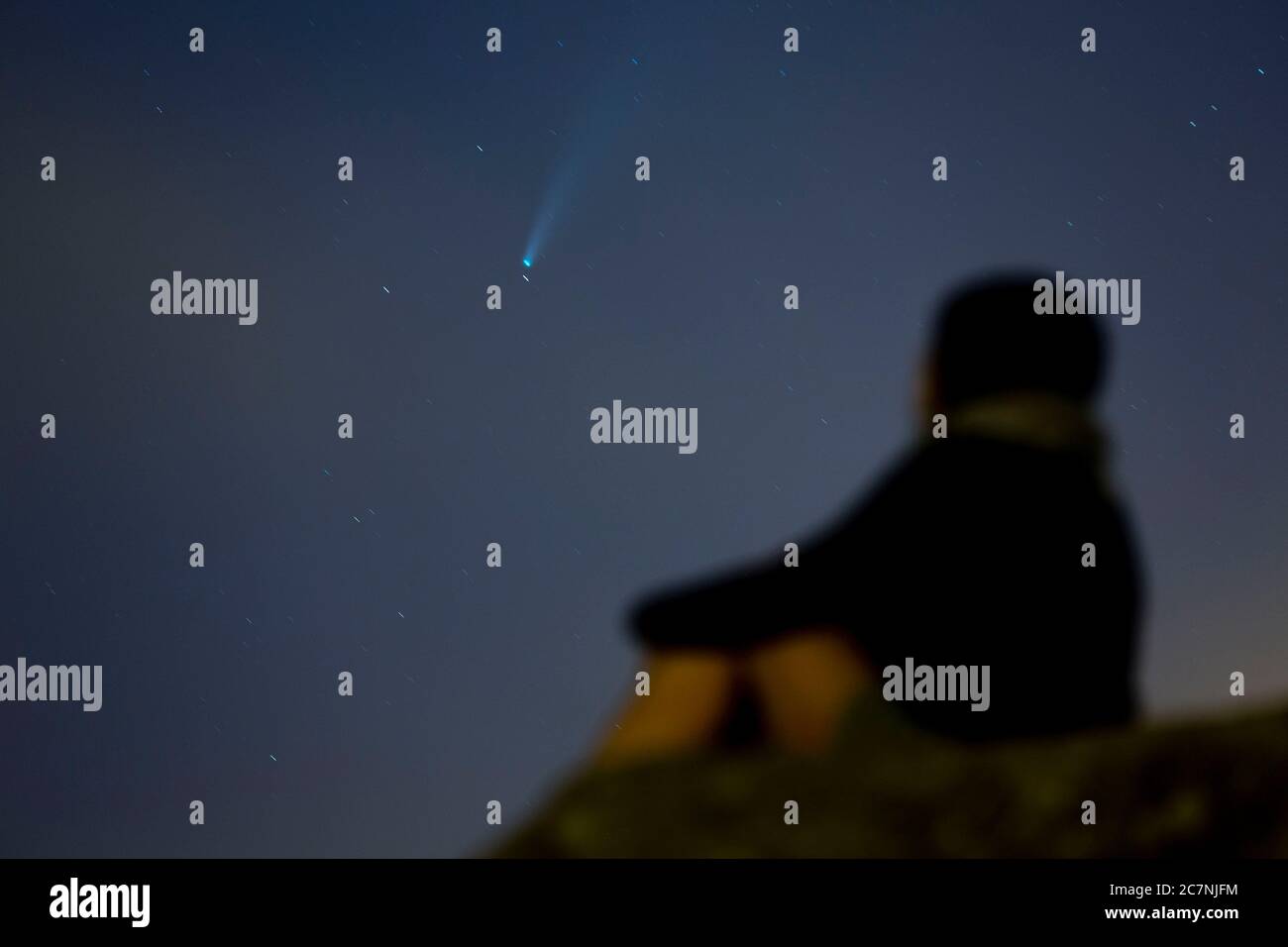 Una ragazza è vista guardare la Comet NEOWISE o C/2020 F3 dopo il tramonto con nuvole di fumo a causa dei forti incendi intorno alla città di Porto, Portogallo. Il 18 luglio 2020. La cometa è stata scoperta il 27 marzo 2020 da NEOWISE, il Near Earth Object Wide-Field Infrared Survey Explorer, che è un telescopio spaziale lanciato dalla NASA nel 2009. Foto Stock