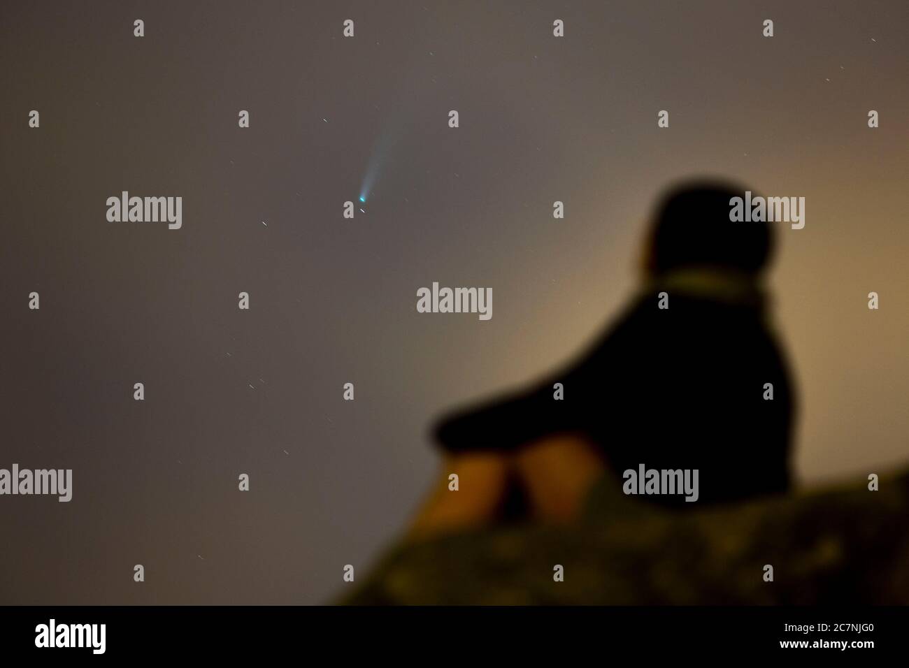 Una ragazza è vista guardare la Comet NEOWISE o C/2020 F3 dopo il tramonto con nuvole di fumo a causa dei forti incendi intorno alla città di Porto, Portogallo. Il 18 luglio 2020. La cometa è stata scoperta il 27 marzo 2020 da NEOWISE, il Near Earth Object Wide-Field Infrared Survey Explorer, che è un telescopio spaziale lanciato dalla NASA nel 2009. Foto Stock