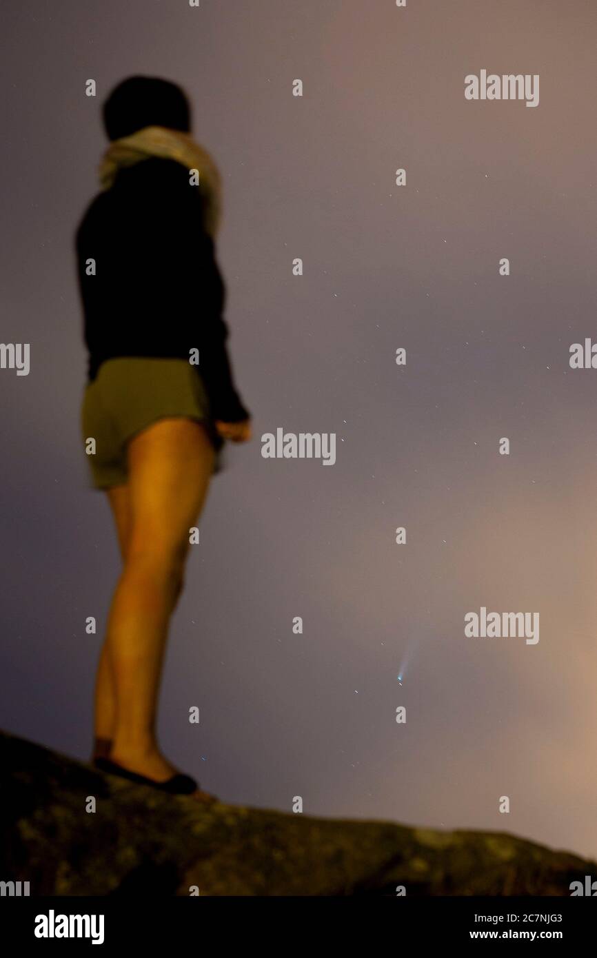 Una ragazza è vista guardare la Comet NEOWISE o C/2020 F3 dopo il tramonto con nuvole di fumo a causa dei forti incendi intorno alla città di Porto, Portogallo. Il 18 luglio 2020. La cometa è stata scoperta il 27 marzo 2020 da NEOWISE, il Near Earth Object Wide-Field Infrared Survey Explorer, che è un telescopio spaziale lanciato dalla NASA nel 2009. Foto Stock
