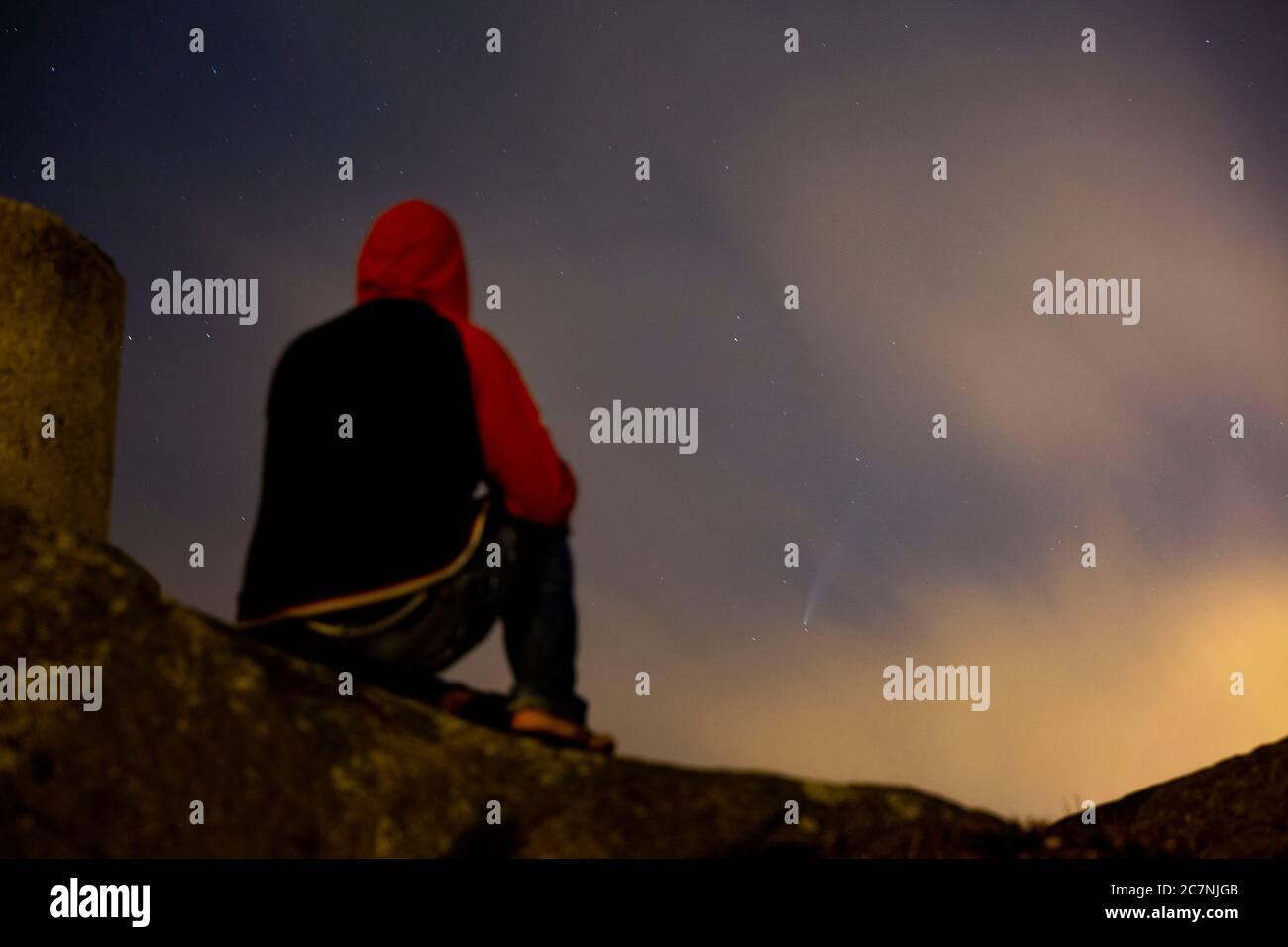 Un uomo è visto guardare la Comet NEOWISE o C/2020 F3 dopo il tramonto con nuvole di fumo a causa dei forti incendi intorno alla città di Porto, Portogallo. Il 18 luglio 2020. La cometa è stata scoperta il 27 marzo 2020 da NEOWISE, il Near Earth Object Wide-Field Infrared Survey Explorer, che è un telescopio spaziale lanciato dalla NASA nel 2009. Foto Stock