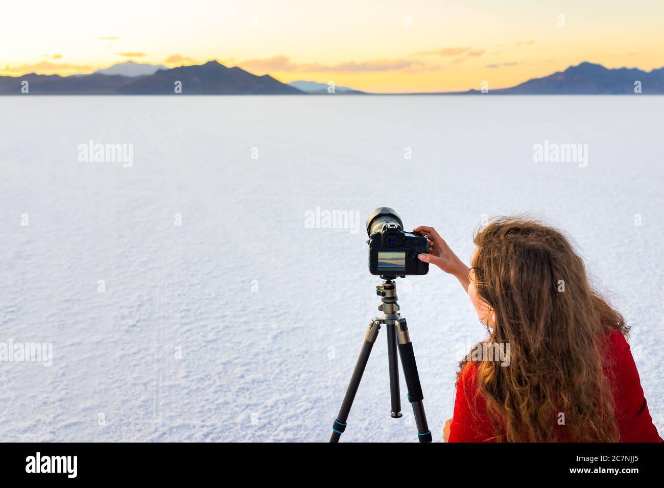 Bonneville Salt Flats colore bianco vicino a Salt Lake City, Utah, al tramonto colorato con una fotografa che fotografa la donna scattando foto della vista utilizzando la fotocamera sul treppiede Foto Stock