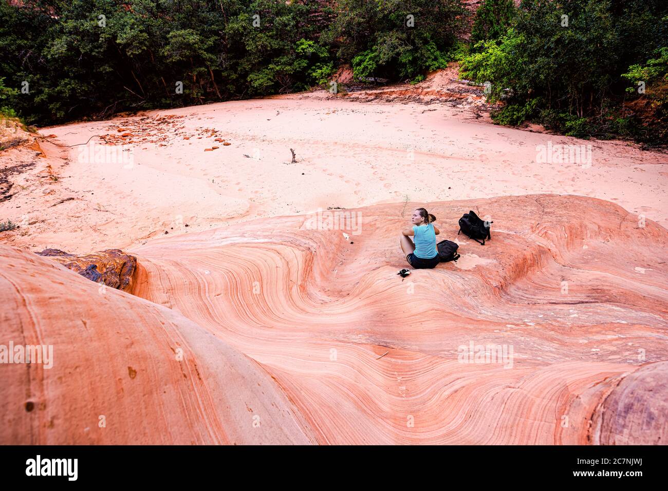 Zion National Park in Utah sul sentiero del Gifford Canyon con una donna seduta riposata da formazioni di arenaria rossa in estate, sopra la vista ad alto angolo Foto Stock