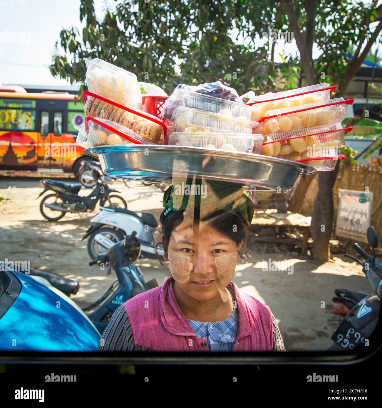 Una donna birmana mostra spuntini in vendita su un vassoio bilanciato sulla sua testa a Mandalay, Myanmar Foto Stock