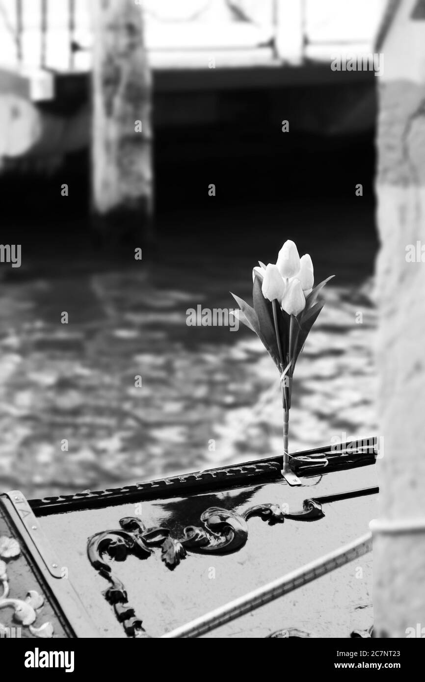 Foto in bianco e nero di un bouquet di tulipani artificiali sul bordo di una barca Foto Stock