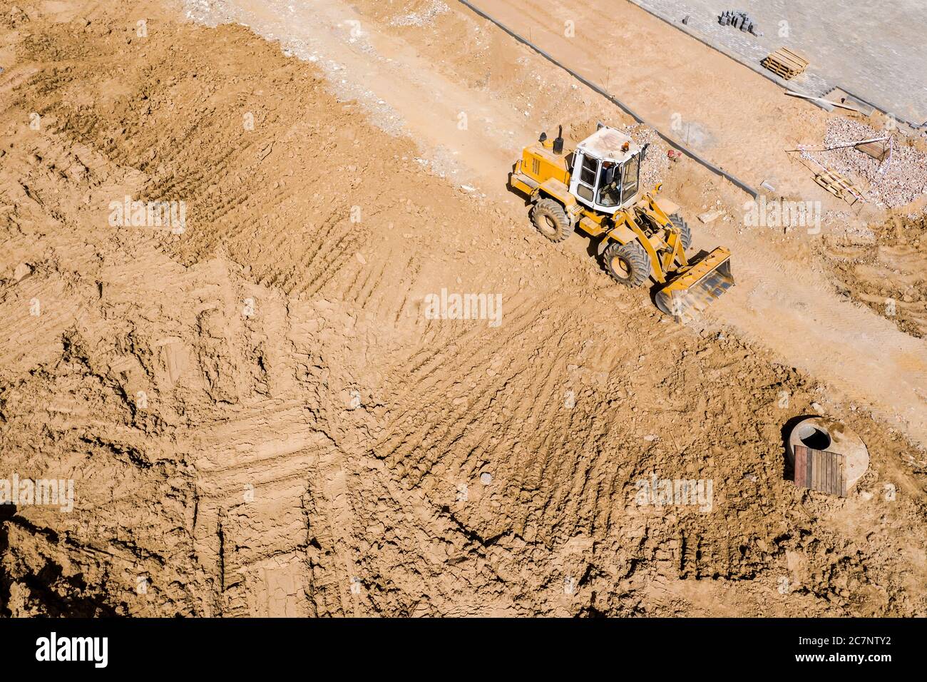 pala caricatrice gommata gialla in cantiere. attrezzatura pesante in fase di livellamento del terreno. vista dall'alto verso il basso dall'alto Foto Stock