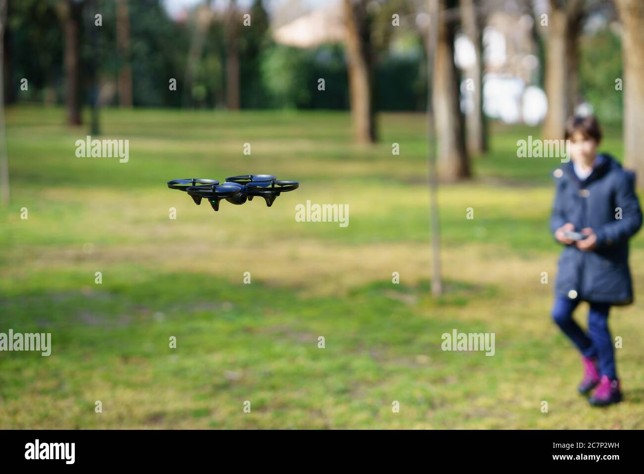 Ragazza di nove anni che fa funzionare drone giocattolo volare con telecomando Foto Stock
