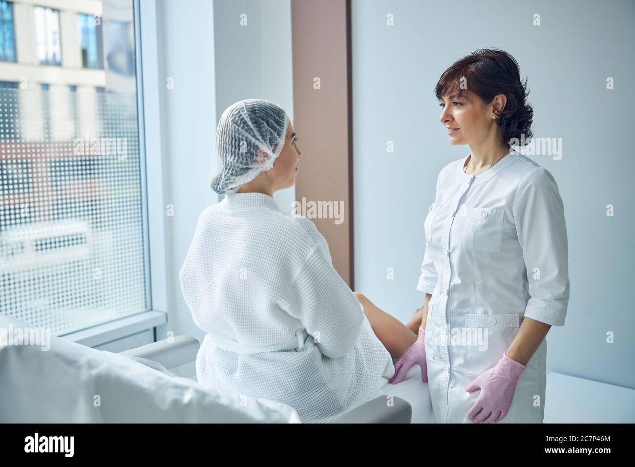 Paziente femminile che ottiene la consultazione iniziale allo studio di bellezza Foto Stock