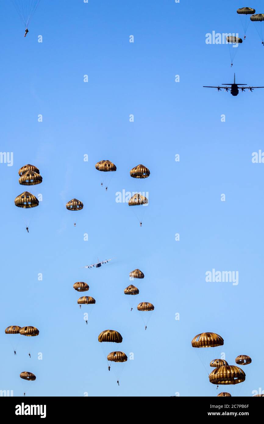Paracadutisti militari paracadutisti paracadutisti che saltano fuori da un aereo di forze aeree in una giornata di cielo blu chiaro. Foto Stock