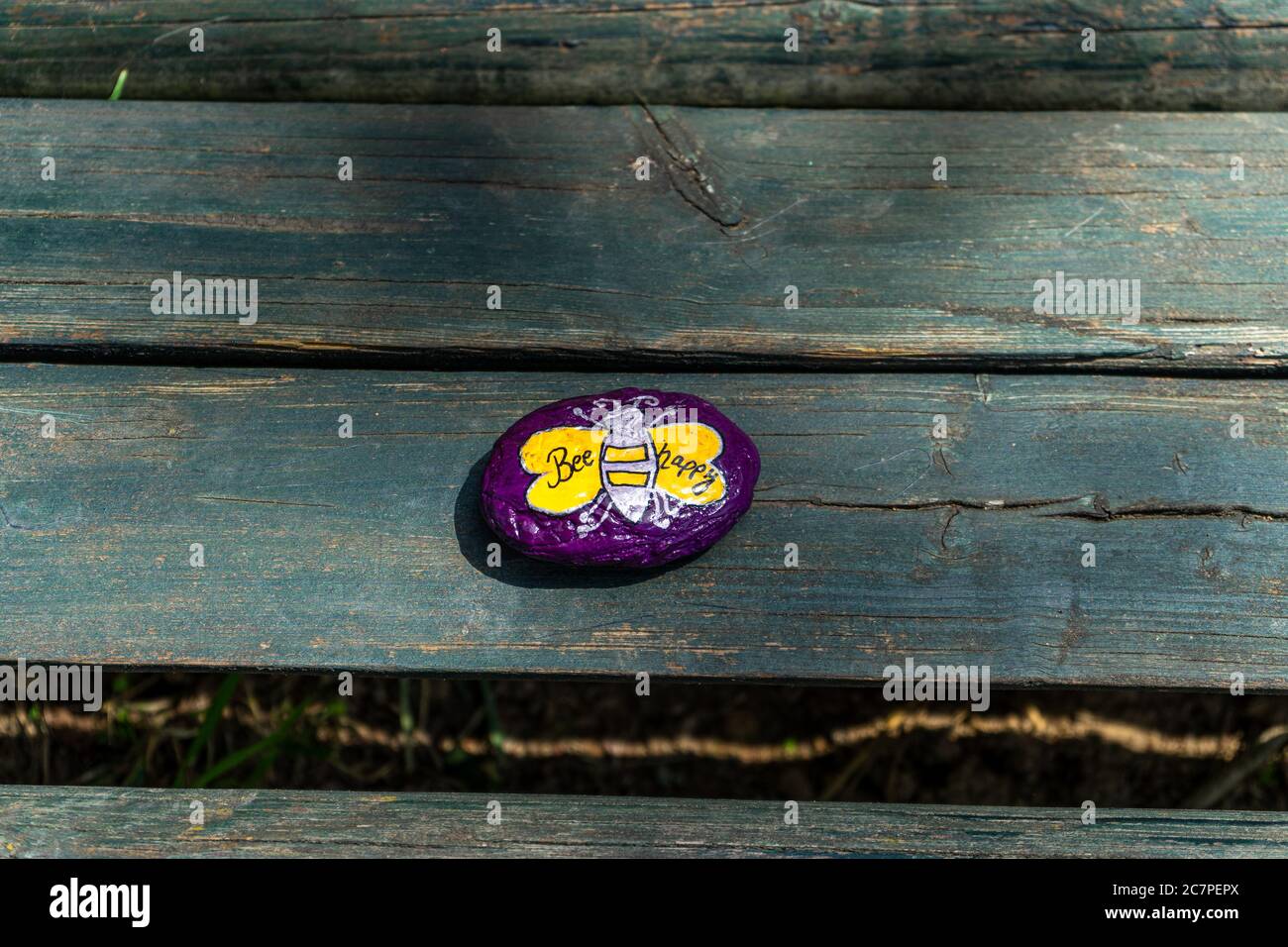 Una pietra colorata con un ape e Bee di testo felice Foto Stock
