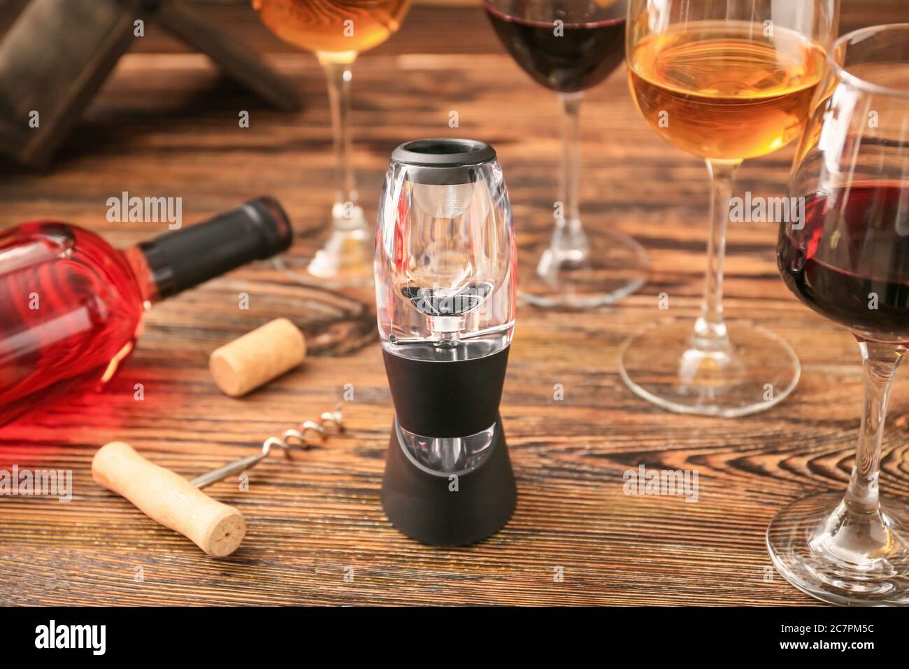 Aeratore per vino con bottiglia e bicchieri su fondo di legno Foto