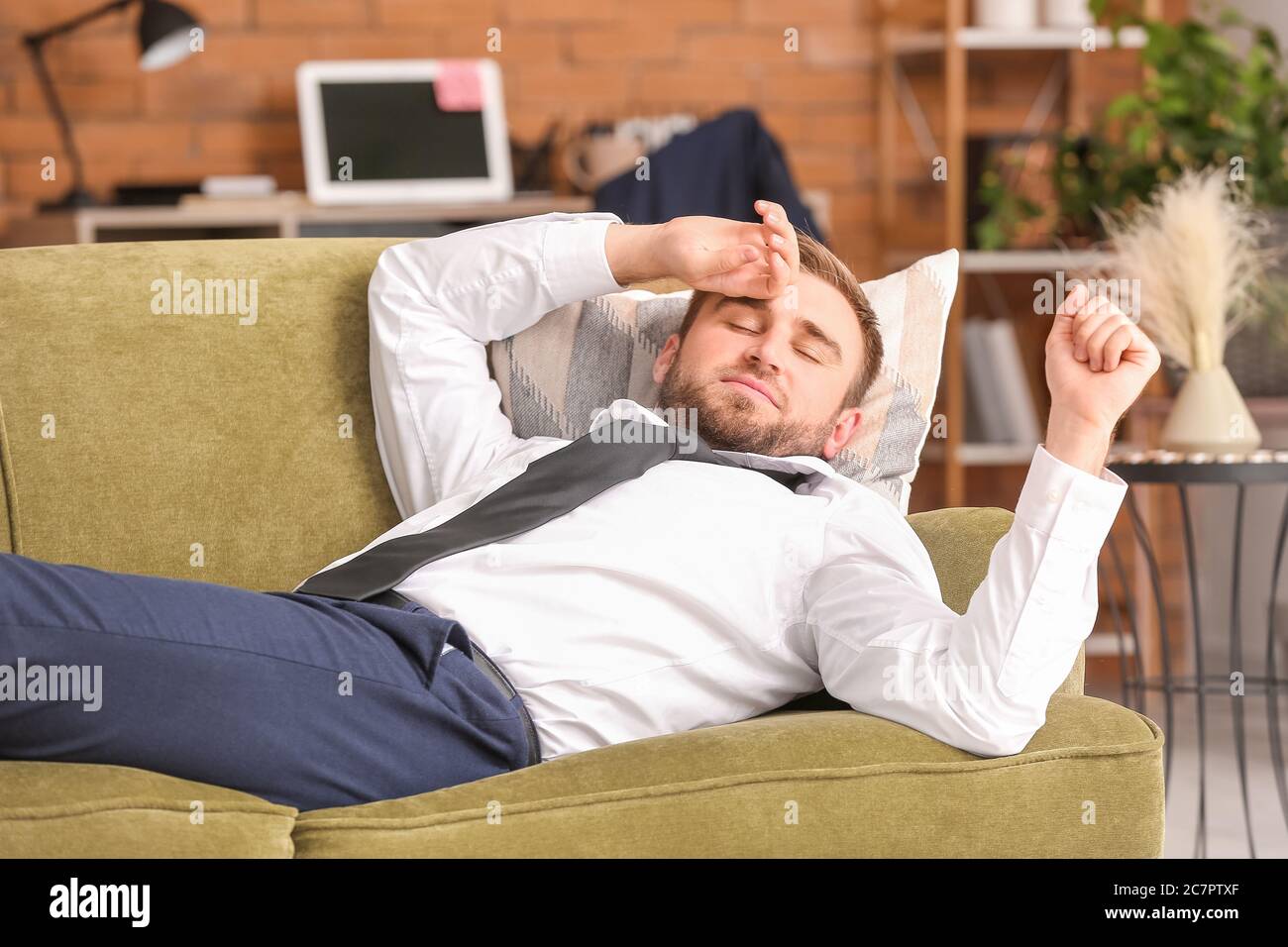 Giovane uomo d'affari che riposa a casa dopo una lunga giornata di lavoro Foto Stock