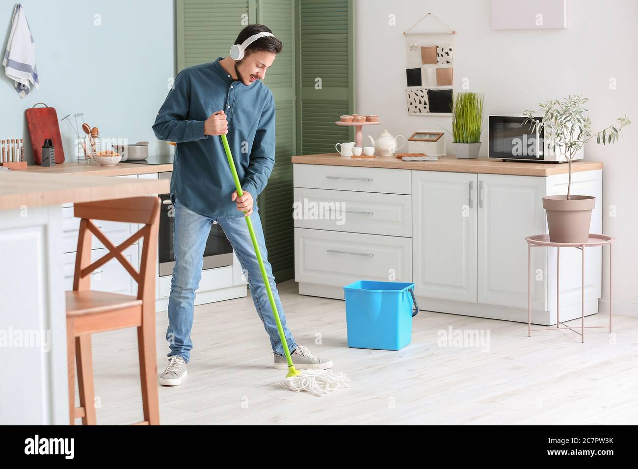 Bel pavimento per la pulizia di un giovane uomo in cucina Foto Stock