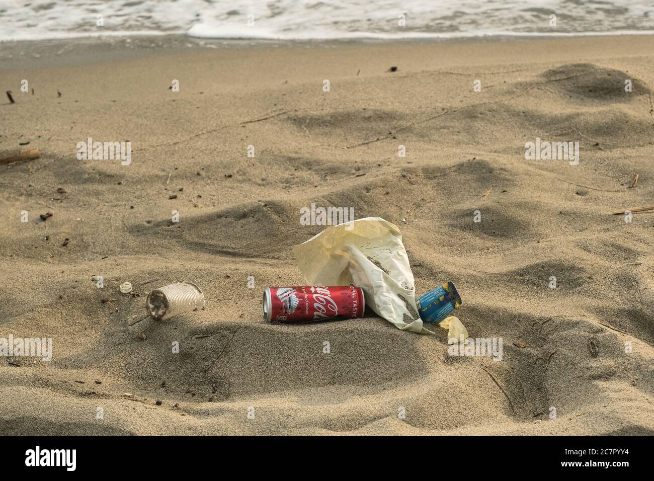 Rifiuti inquinamento sulla spiaggia sabbiosa del mare, vetro di plastica, coke può imballaggio Foto Stock