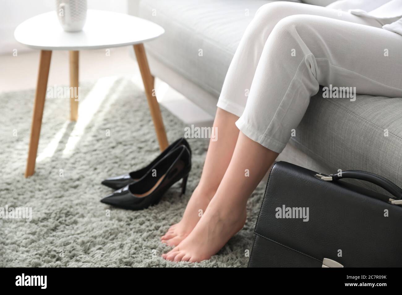Donna d'affari che si rilassa sul divano dopo il lavoro a casa Foto Stock