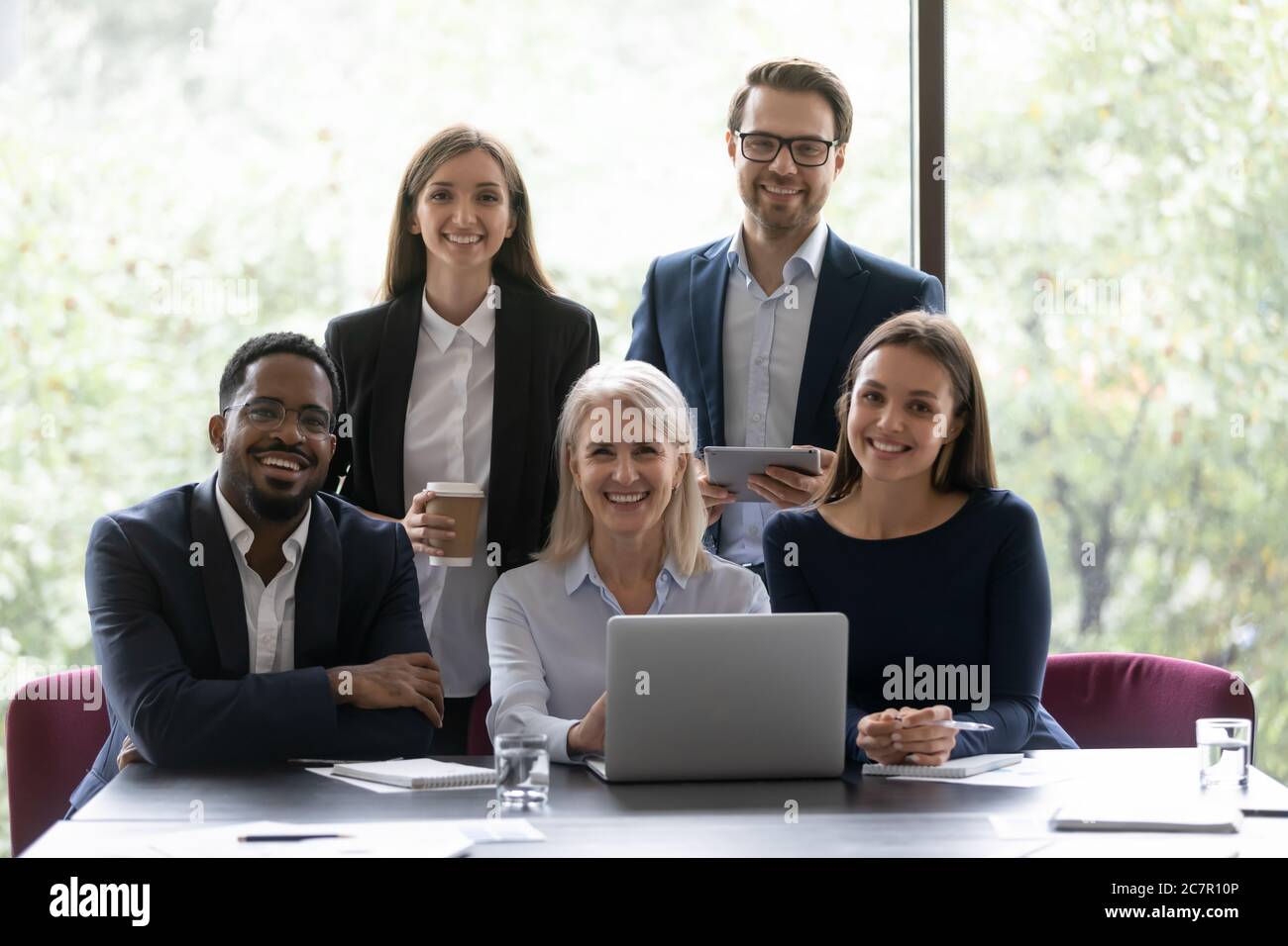 I colleghi multi nazionali si siedono in posa per la fotocamera Foto Stock