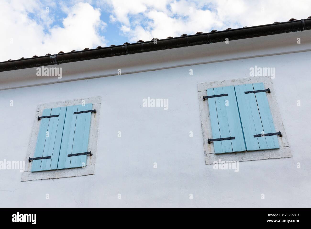 Vecchia casa tradizionale con porta blu chiaro e persiane nel villaggio di Hrastovlje, slovenia Foto Stock
