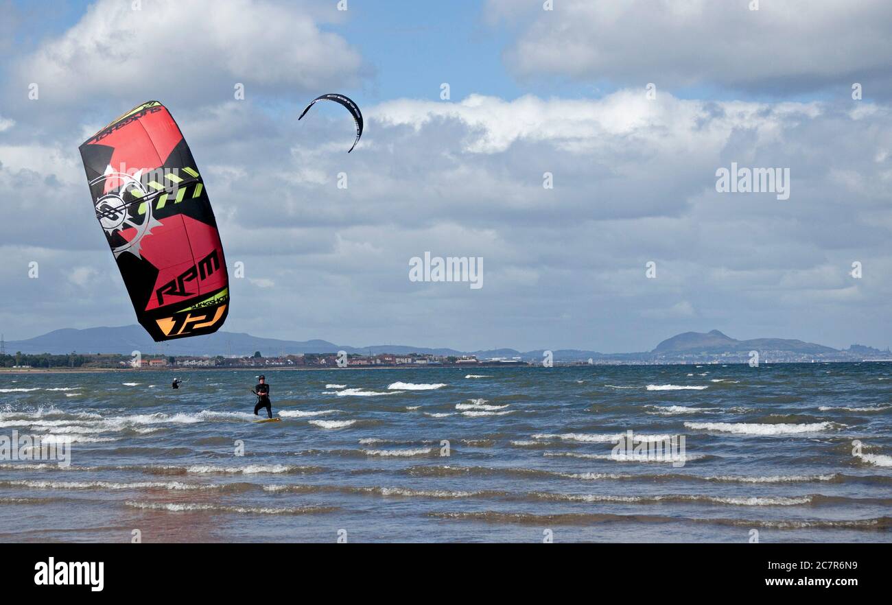 Longniddry, East Lothian, Scozia, Regno Unito. 19 luglio 2020. Nella foto: Il kite surfer Natalie ha afferrato 10 minuti di vento dalla direzione ovest prima che le condizioni diventassero meno favorevoli e le raffiche dove meno adatte per l'ascensore sul Firth of Forth, con la città di Edimburgo e Arthurs Seat in background. Temperatura di 16 gradi di luce e nuvolosità prima di mezzogiorno quando la nube più spessa si è spostata. Foto Stock