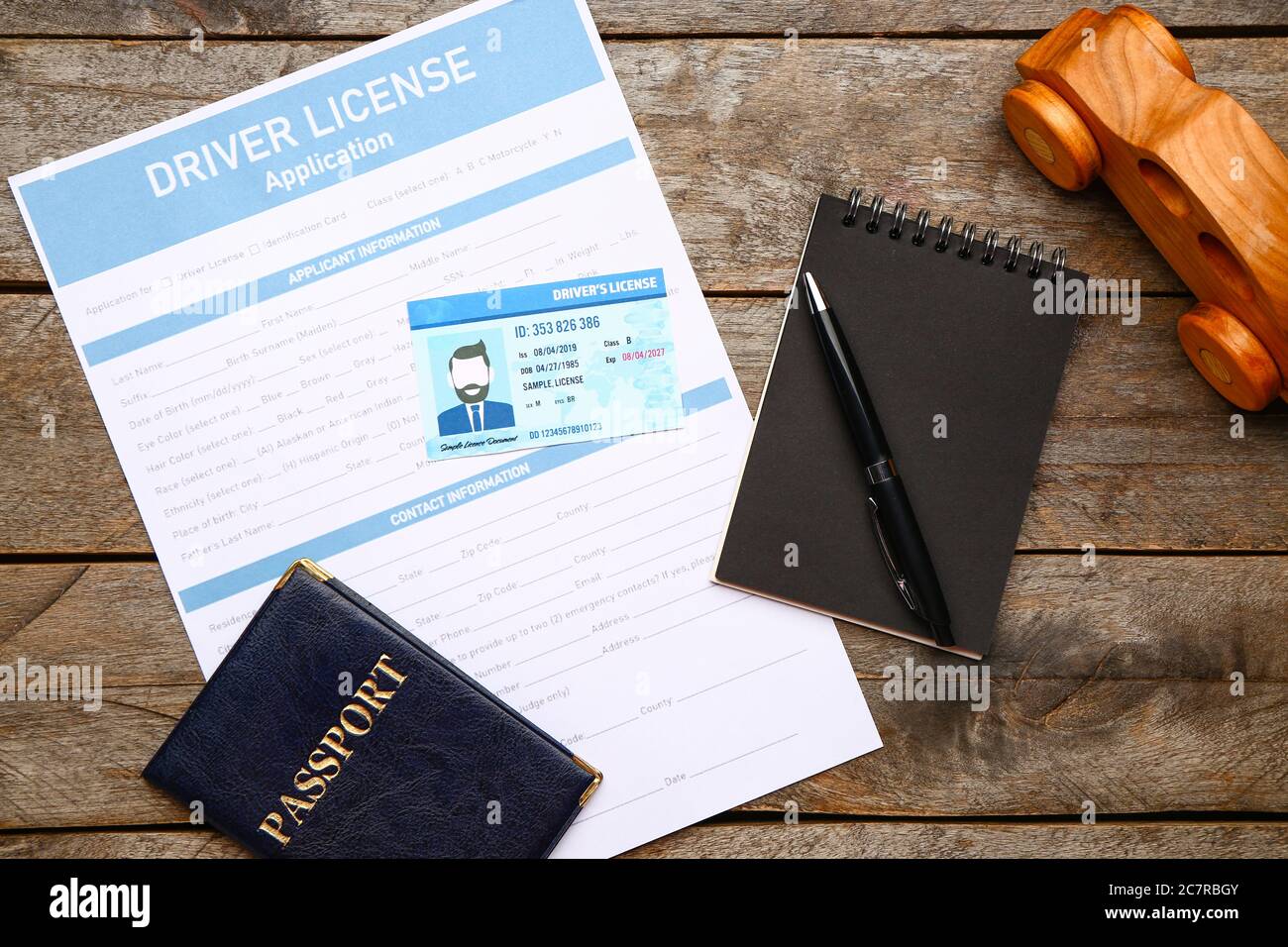Patente di guida con modulo di richiesta, passaporto e taccuino su sfondo di legno Foto Stock