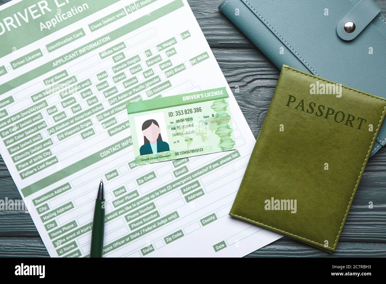 Patente di guida con modulo di richiesta, passaporto e portafoglio su sfondo di legno Foto Stock