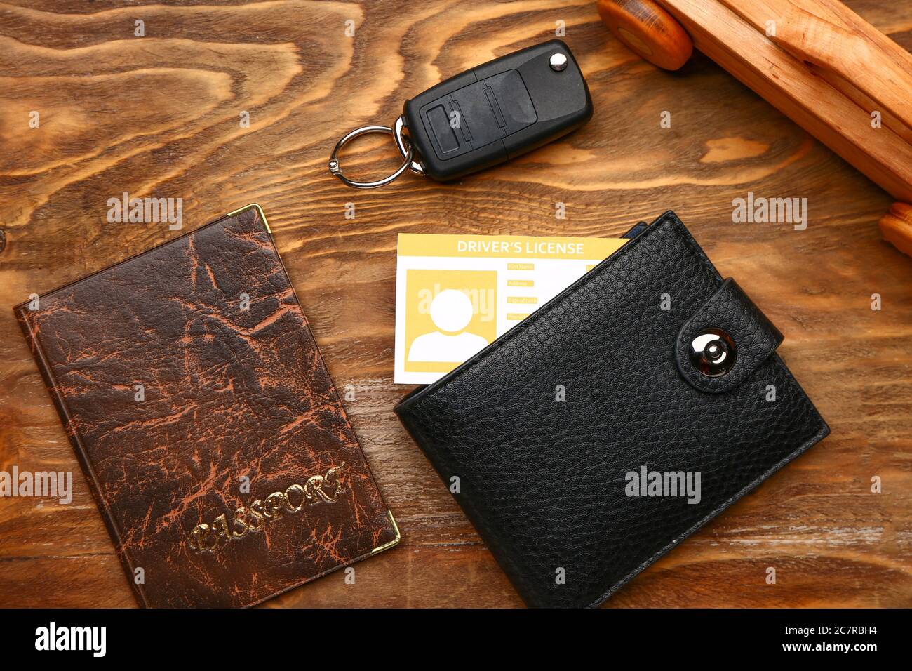 Patente di guida con portafoglio, passaporto e chiave dell'auto su sfondo di legno Foto Stock