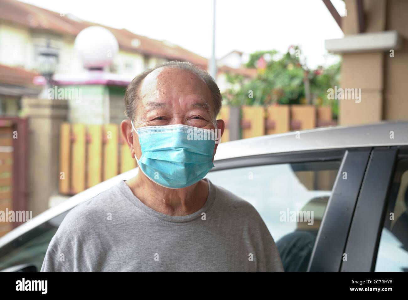 Uomo anziano con maschera medica a casa. Rimani a casa per ridurre il rischio di Covid-19. Foto Stock