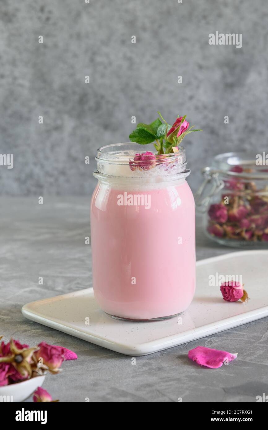 Latte di luna di rosa in vaso di muratore su sfondo grigio. Primo piano. Ayurveda bevanda calda. Bello in caso di insonnia. Foto Stock