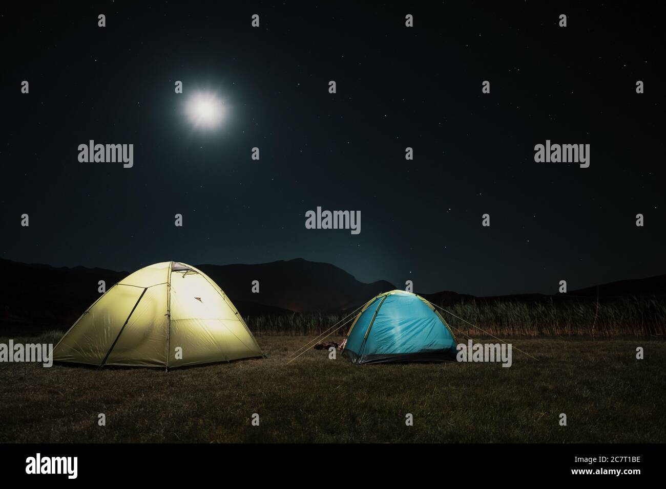 Campeggio in montagna sotto la luna. Una tenda si accampò e si illuminò sotto il cielo. Foto Stock