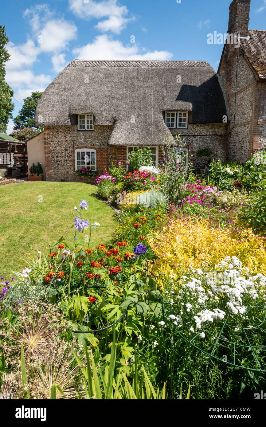Pittoresco cottage con tetto in paglia e giardino fiorito durante l'estate a LudgerShall, Wiltshire, Inghilterra, Regno Unito Foto Stock