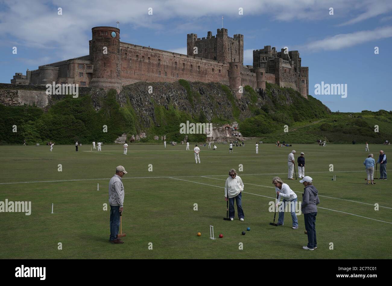 Il club di cricket di Bamburgh (indietro) gioca la loro prima partita di cricket dal covid-19 contro i Cavalieri di Belmont , Durham, sotto le mura del castello di Bamburgh in Northumberland. Foto Stock