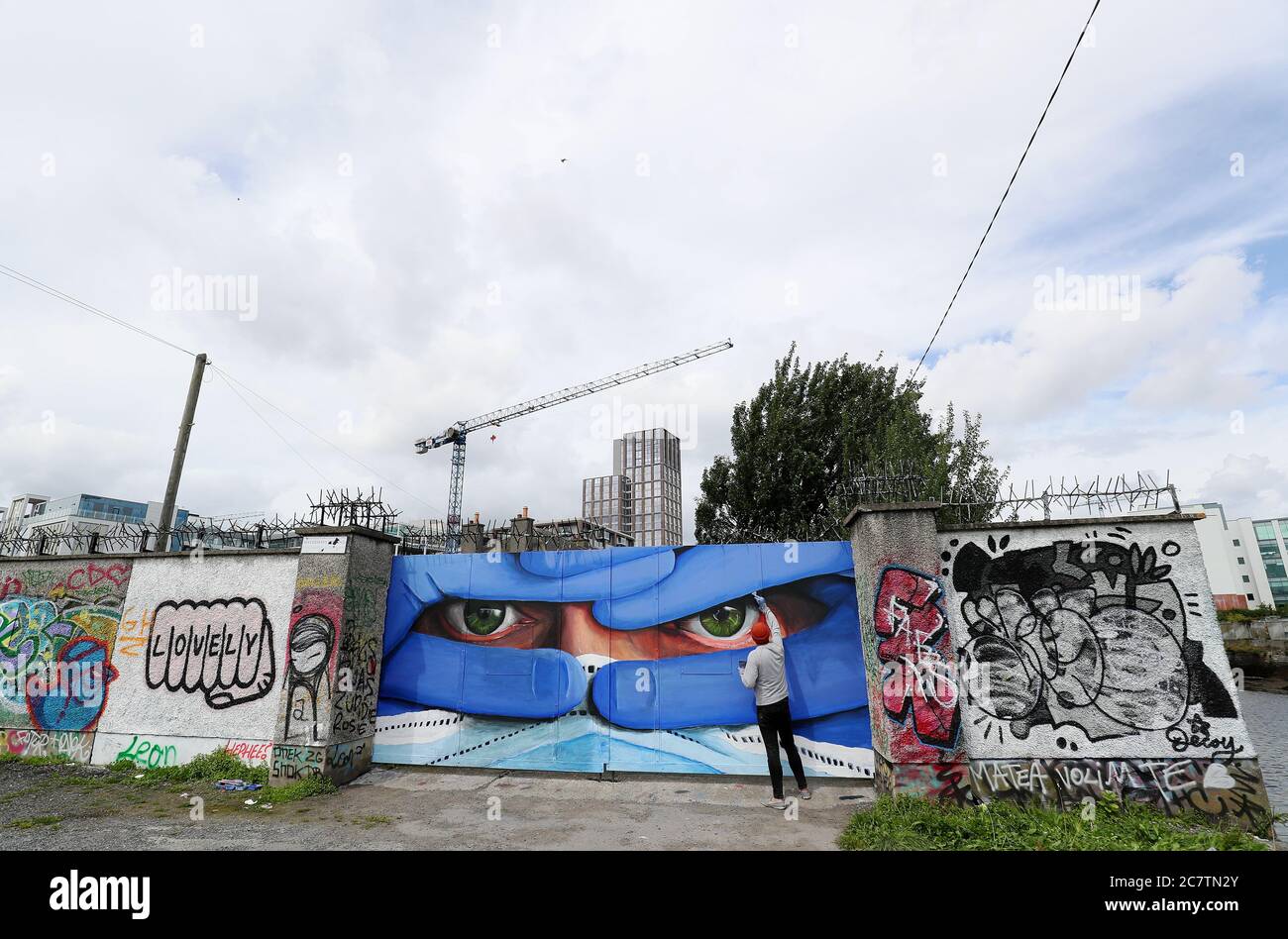 L'artista di Dublino, l'amianto, mette i tocchi finali all'ultimo posto nella sua serie di ritratti di maschere, il murale nel centro di Dublino è intitolato "Proteggi noi" e sottolinea la necessità di indossare maschere protettive nel tentativo di controllare la diffusione di Covid-19. Foto Stock