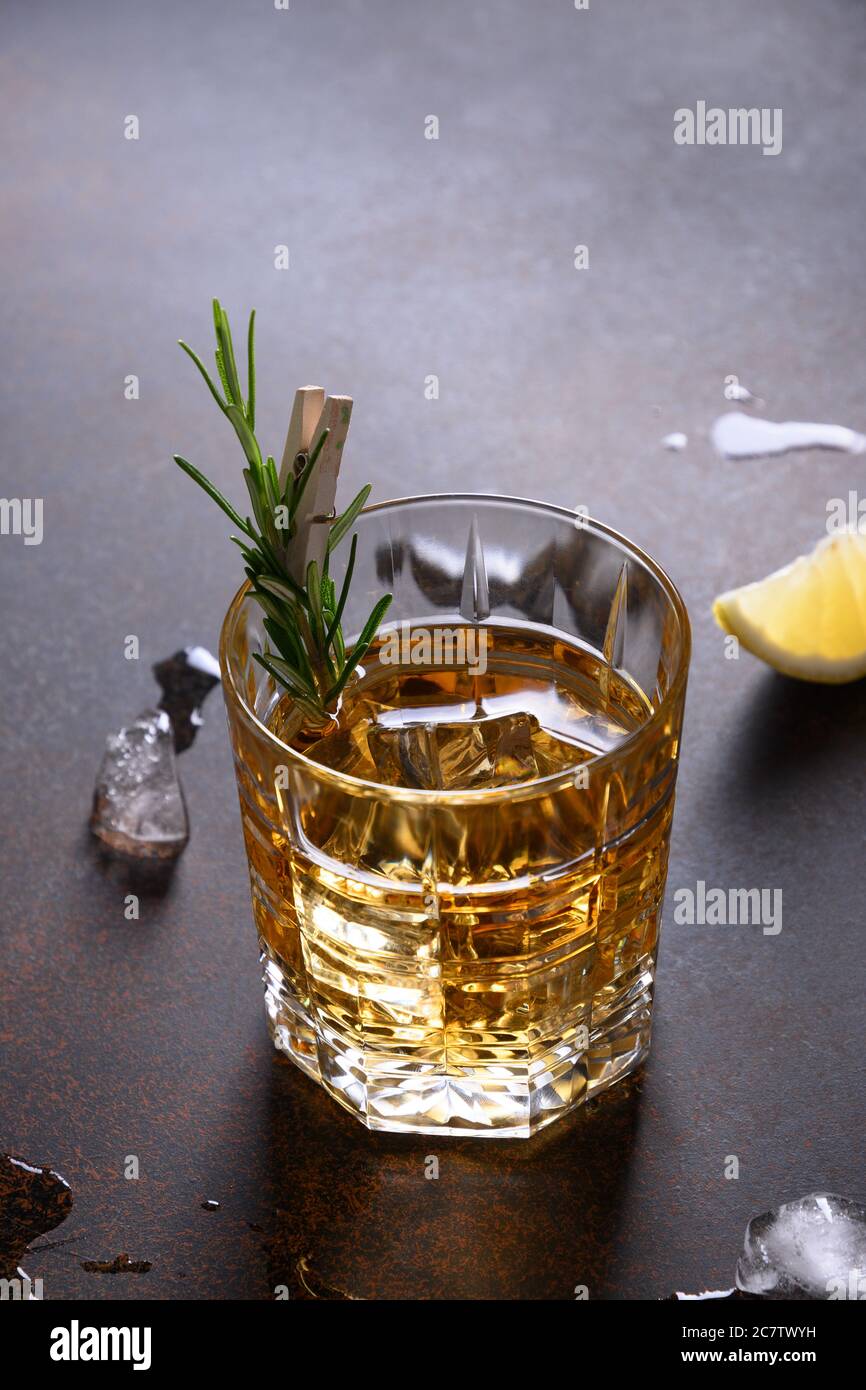Un colpo di whisky con rosmarino su marrone scuro. Orientamento verticale. Foto Stock