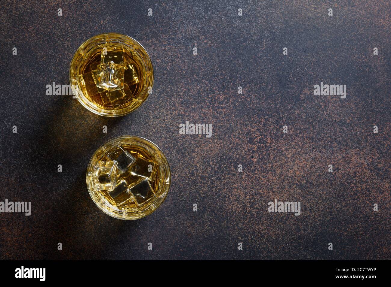 Twoshot di whisky con cubetto di ghiaccio su sfondo marrone scuro. Vista dall'alto. Spazio di copia. Foto Stock