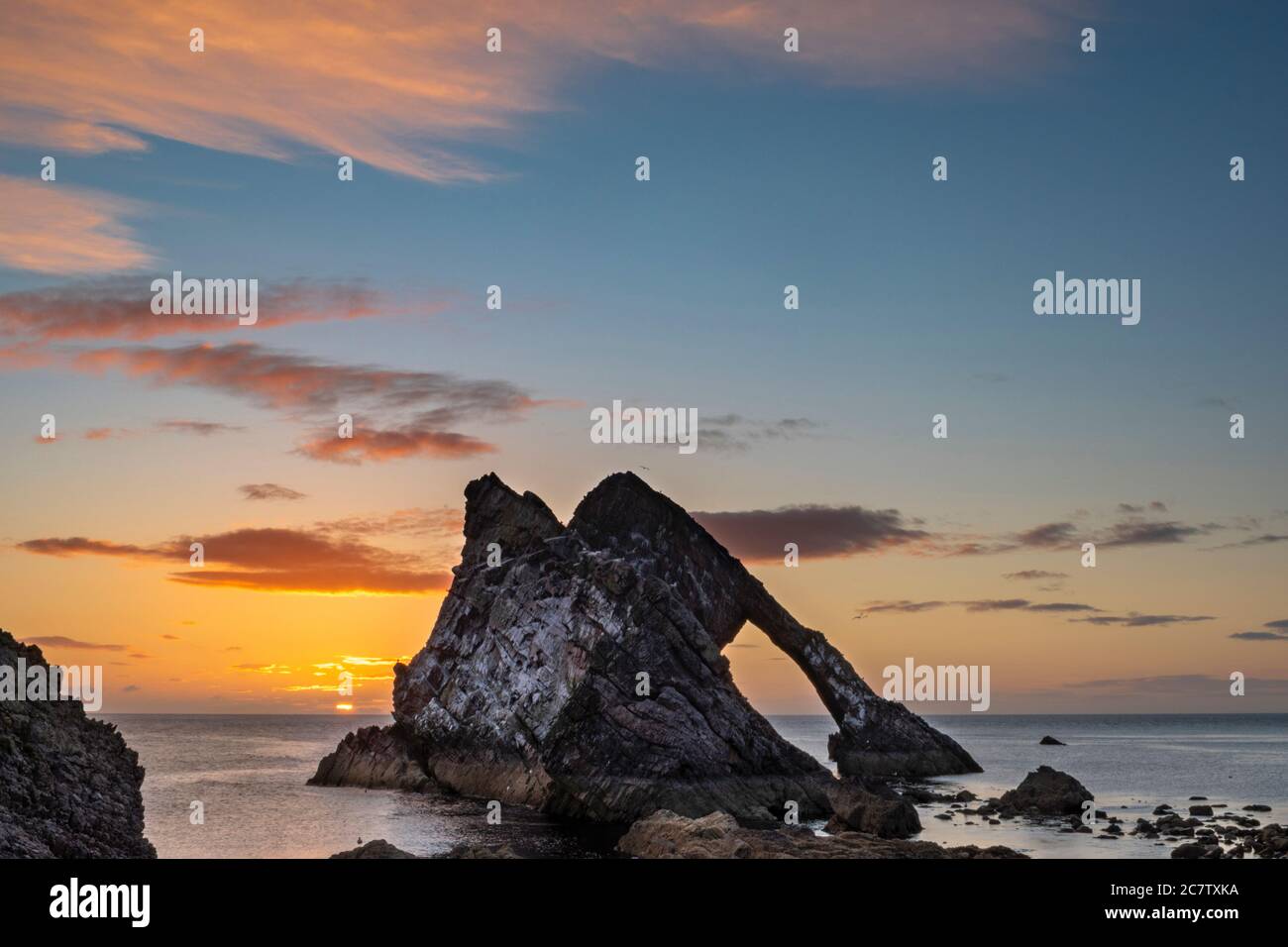 ARCO FIODLE ROCK PORTKNOCKIE MORAY COSTA SCOZIA ESTATE UNA MATTINA ALBA IN LUGLIO NUVOLE COLORATE E SOLE APPENA CRESCENTE Foto Stock