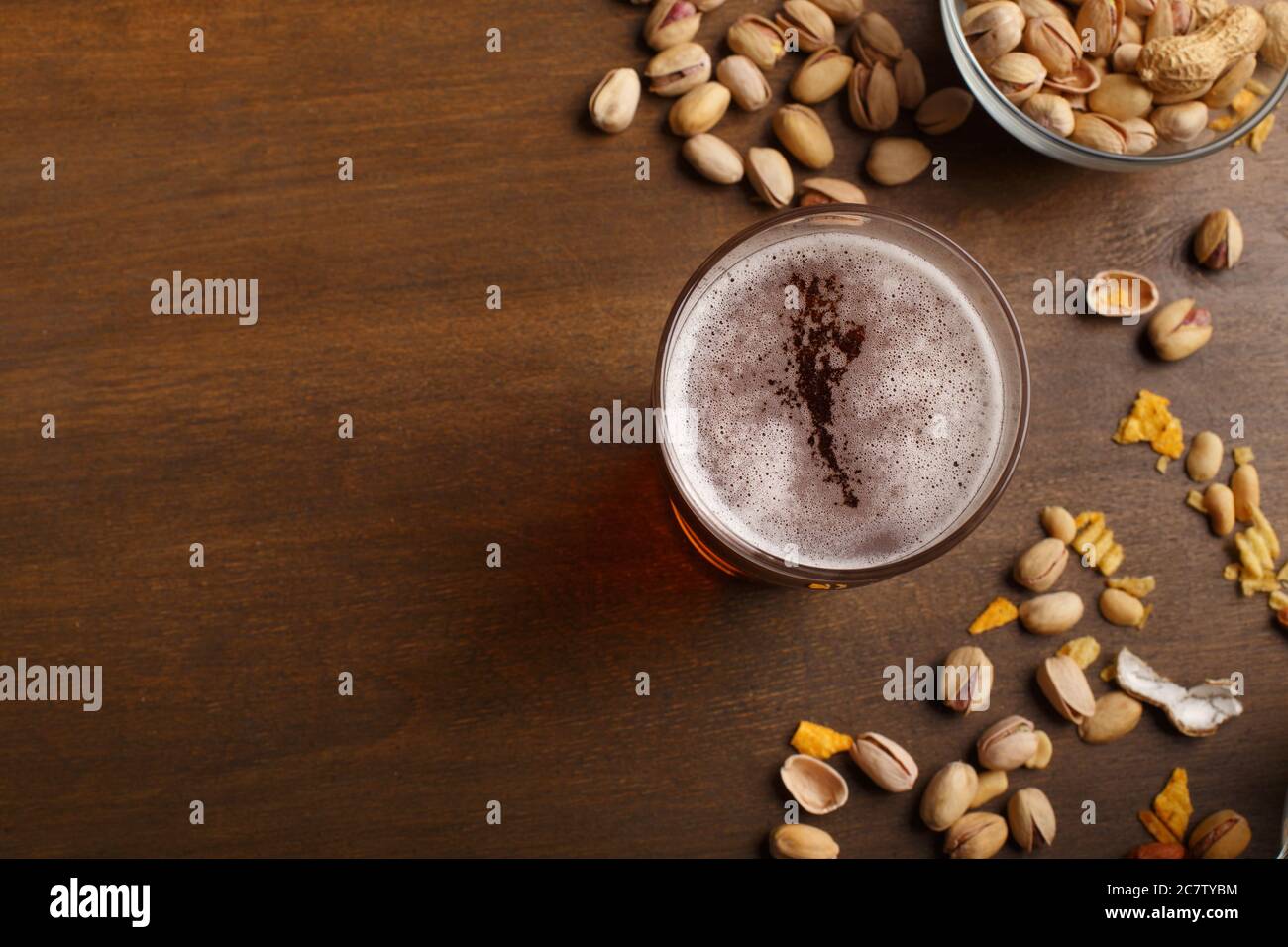 Oktoberfest in pub. Smartphone sul tavolo, vicino sono un bicchiere di birra con schiuma e pistacchi Foto Stock