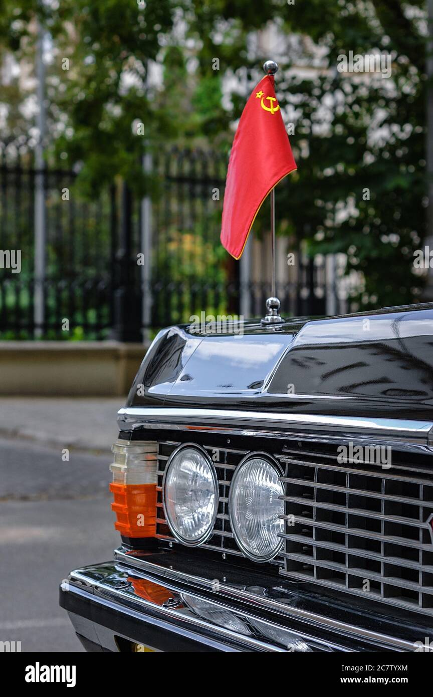 Auto nera classica con la bandiera dell'URSS sul cofano. Frammento di un'auto d'epoca sulla strada. Foto Stock