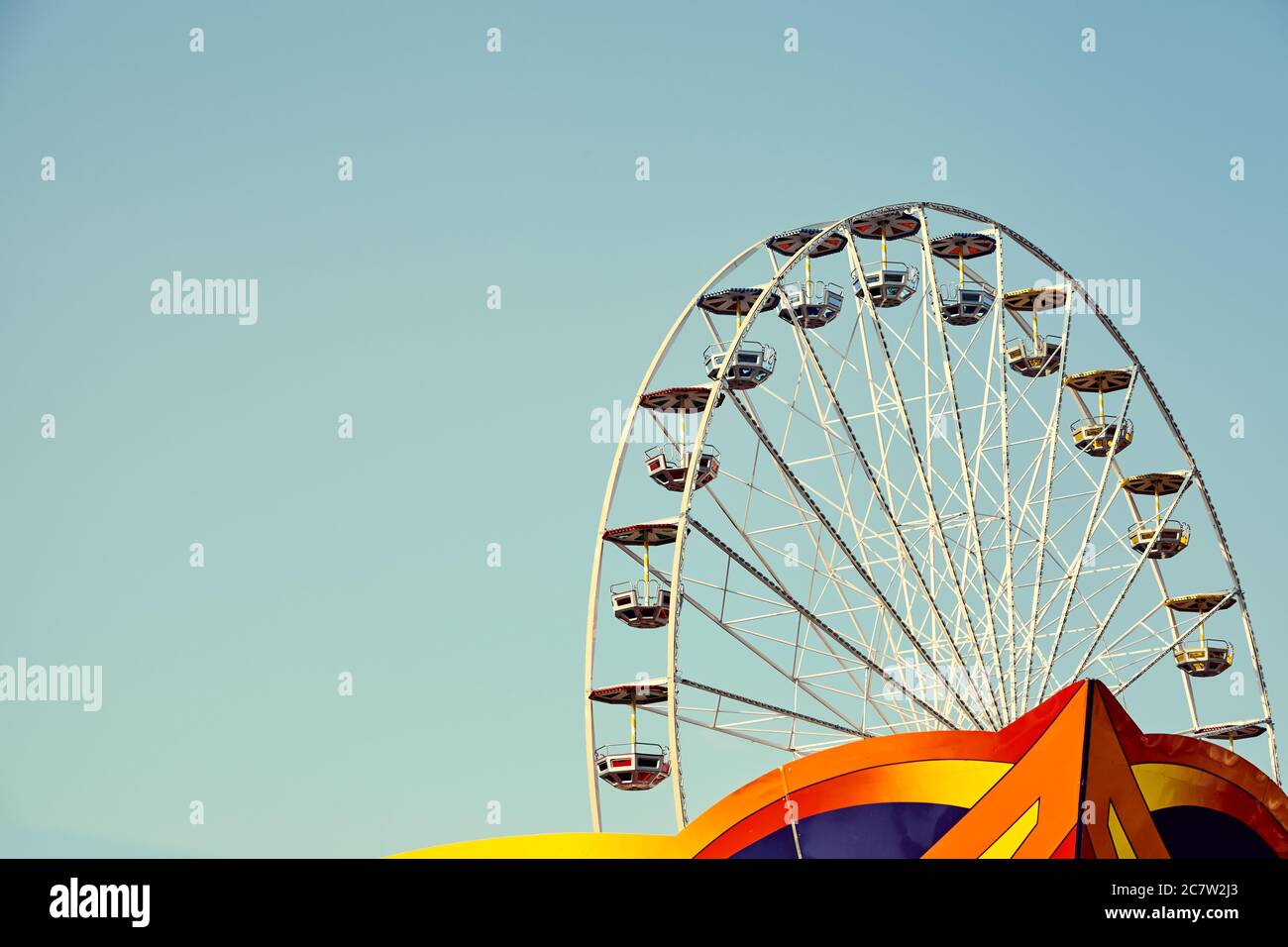 Immagine retrò di una ruota panoramica in un parco divertimenti con cielo senza nuvole, spazio per il testo. Foto Stock