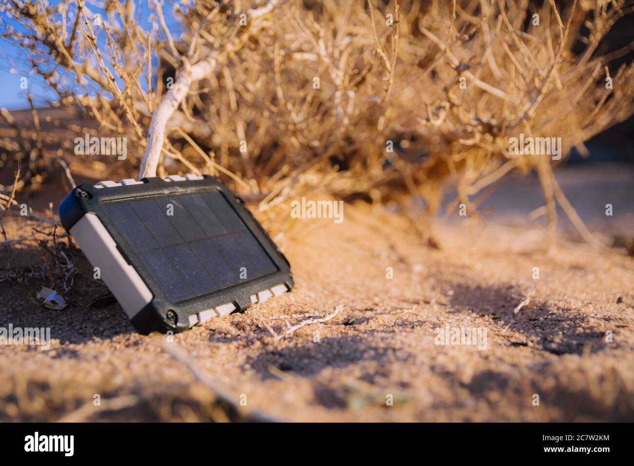 Robusto power bank con pannello solare che carica l'elettricità in natura e sabbia del deserto Foto Stock