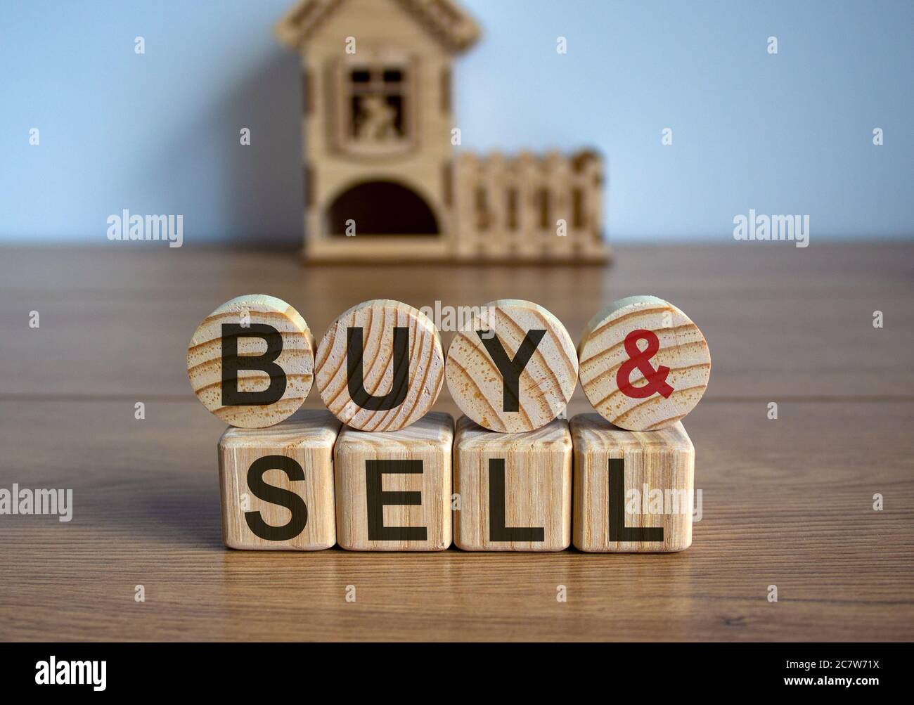 Cubi e cerchi formano le parole 'buy sell' di fronte a una casa in miniatura. Foto Stock