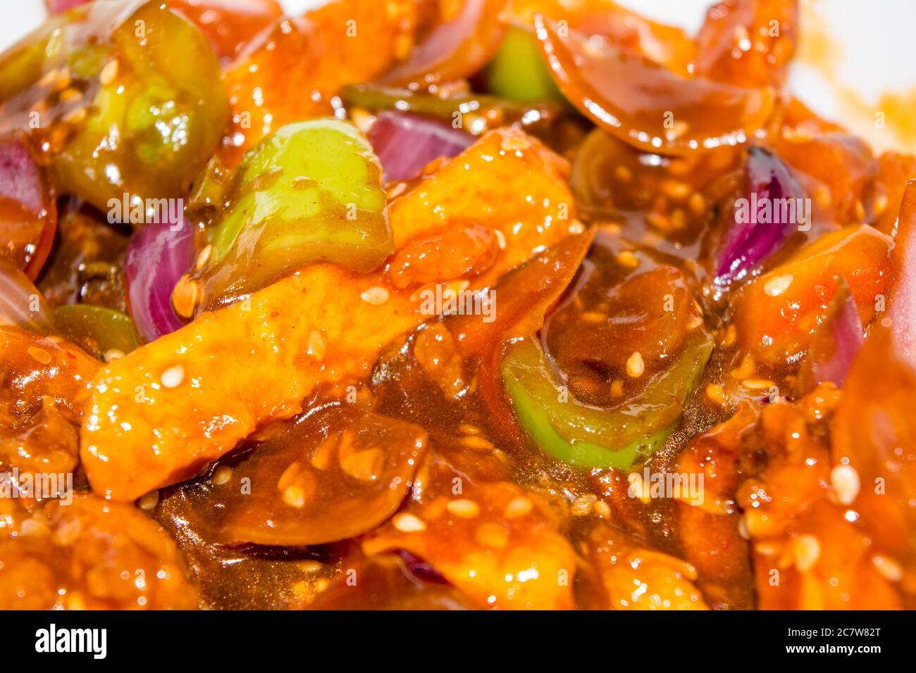 Patate al peperoncino al miele in salsa piccante, semi di sesamo e cipolle verdi da vicino, cibo popolare indiano-cinese. Fuoco selettivo Foto Stock