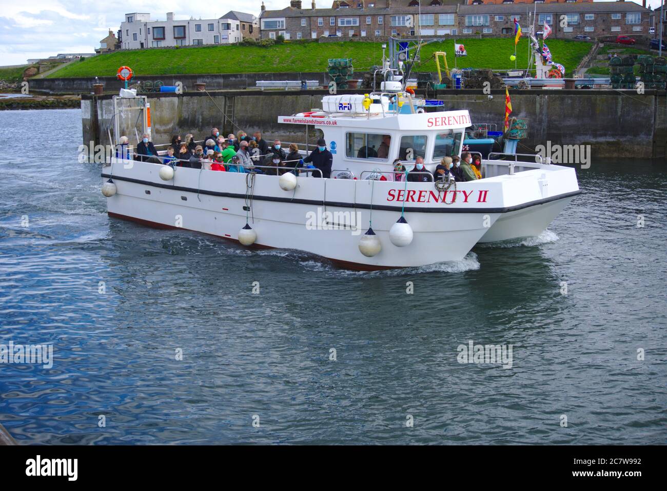 Il catamarano Serenity II si rialloggia al porto delle Seahouses dopo un viaggio in barca alle isole Farne (passeggeri che indossano maschere a causa della pandemia di Covid-19). Foto Stock