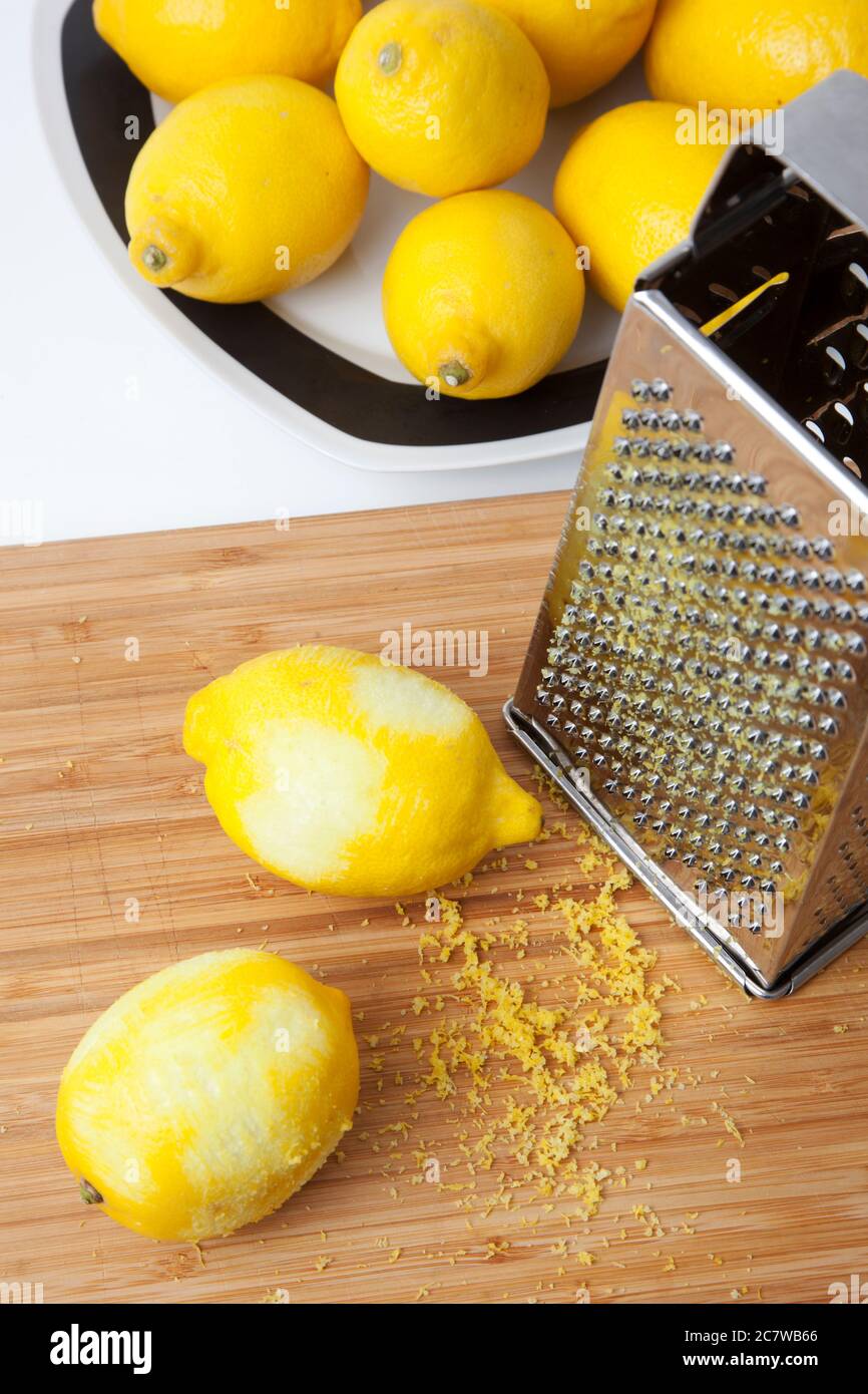 Limoni in un piatto e su una tavola che vengono grattugiati per la loro scorza Foto Stock