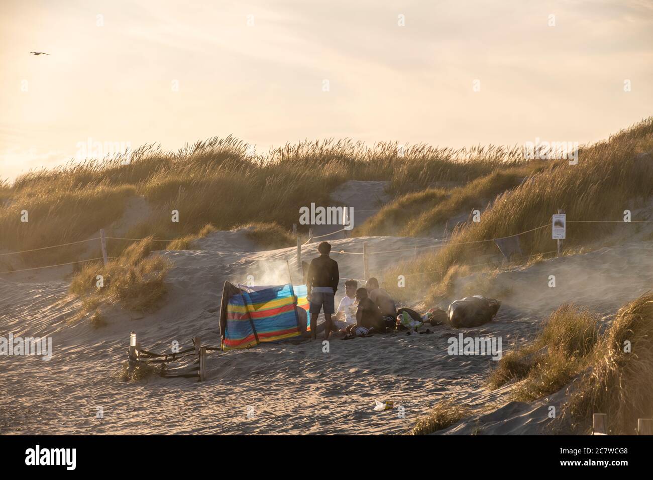 Goditi un barbecue sulla spiaggia a West Wittering in Inghilterra mentre il sole tramonta Foto Stock