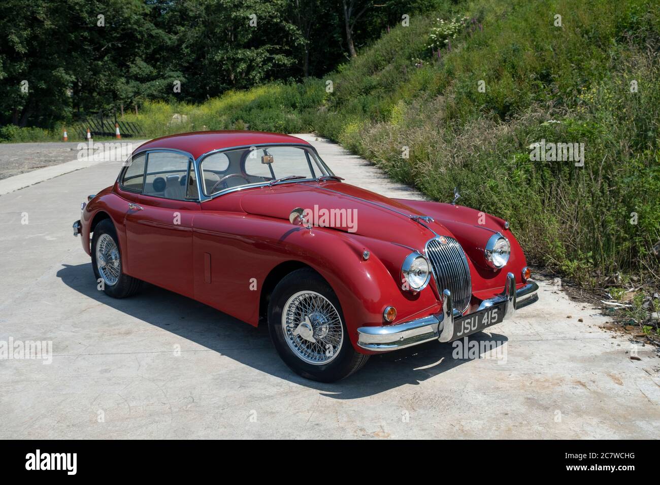 Red Nineteen Fifties Jaguar XK150 coupé parcheggiato su una corsia di campagna nello Yorkshire in una soleggiata giornata estiva Foto Stock