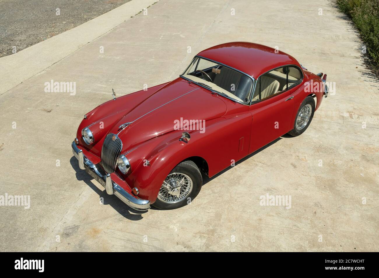 Red Nineteen Fifties Jaguar XK150 coupé parcheggiato su una corsia di campagna nello Yorkshire in una soleggiata giornata estiva Foto Stock