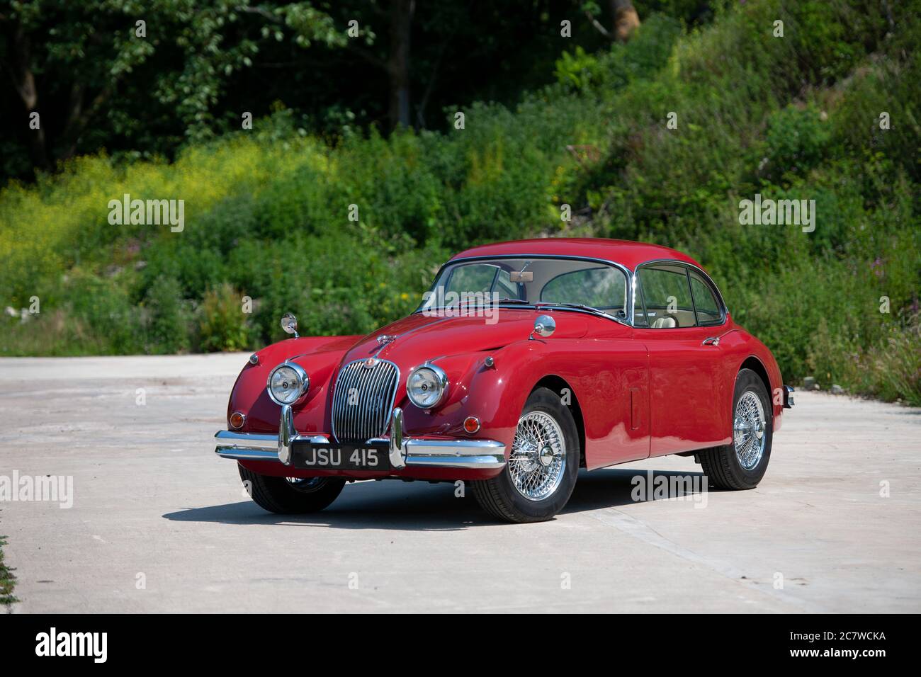 Red Nineteen Fifties Jaguar XK150 coupé parcheggiato su una corsia di campagna nello Yorkshire in una soleggiata giornata estiva Foto Stock