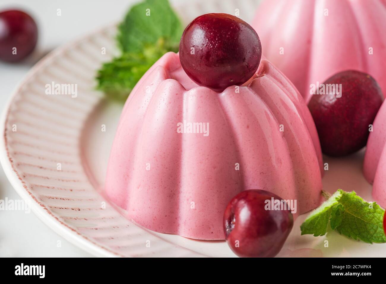 Dessert panna cotta con ciliegie fresche e menta. Dessert salutari all'italiana. Primo piano Foto Stock