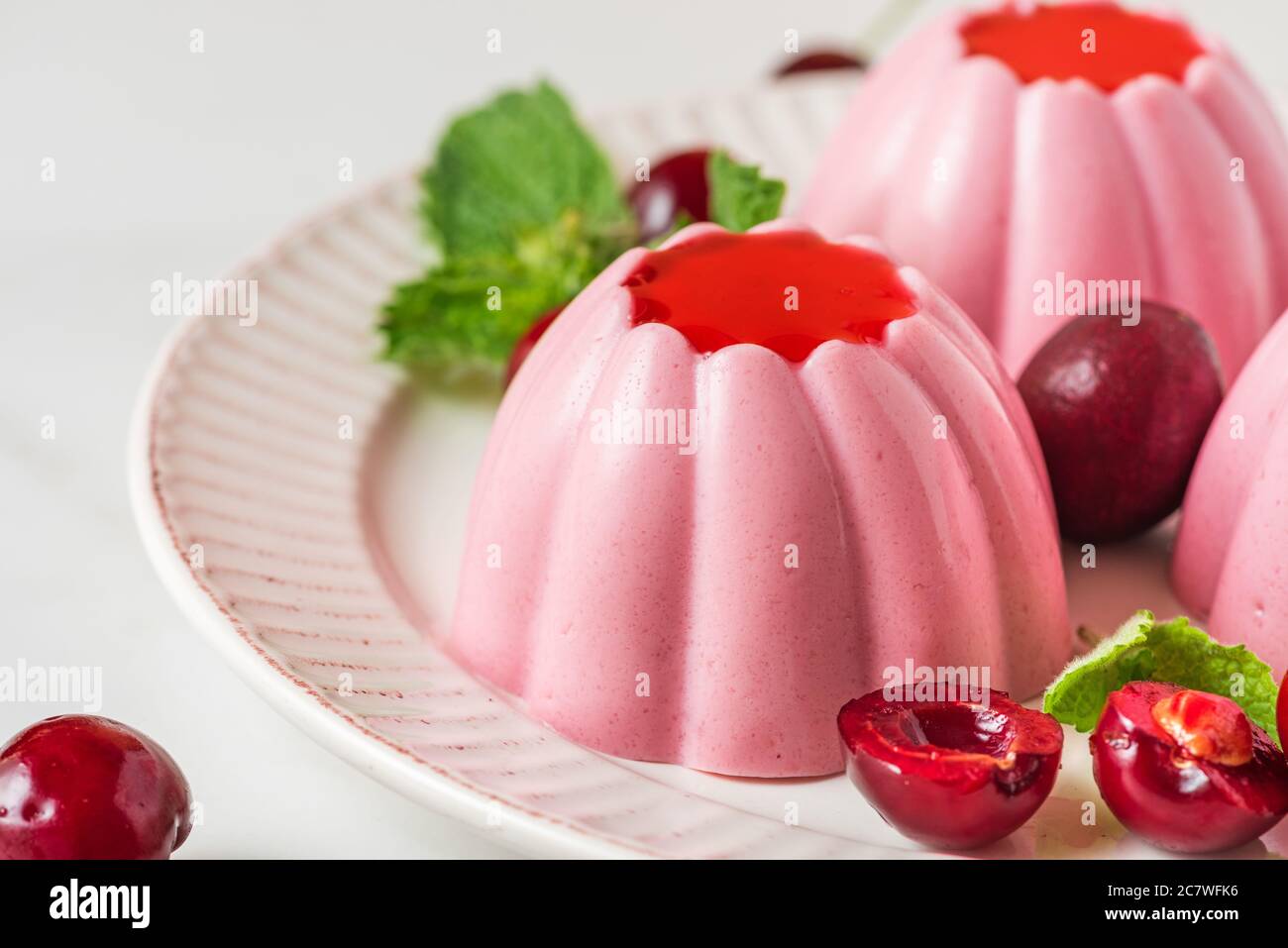 Dessert panna cotta con ciliegie fresche, sciroppo e menta. Cibo vegano italiano sano. Primo piano Foto Stock