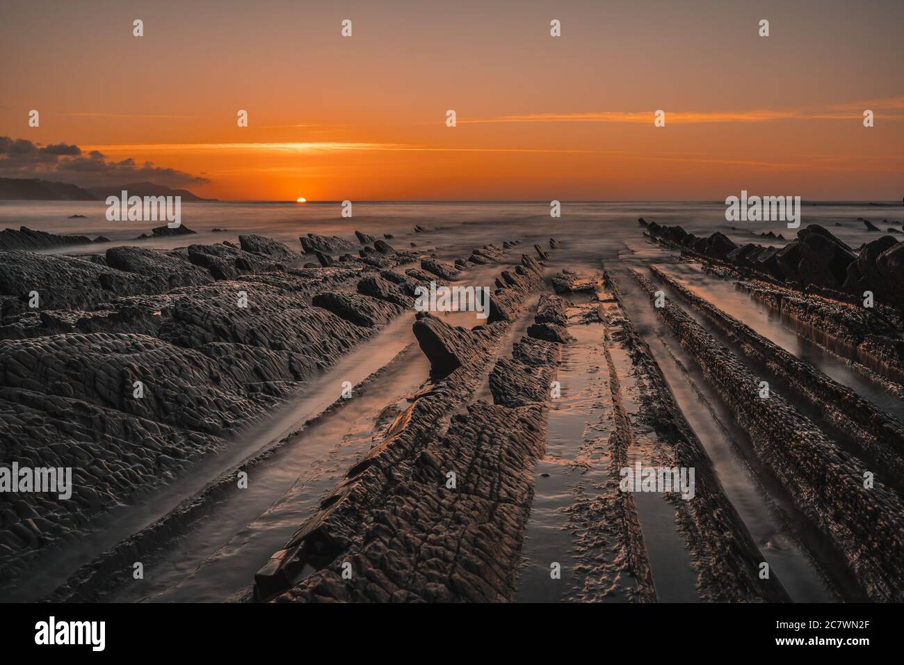 Tramonto arancione sul flysch della spiaggia di Sakoneta nella città di Deba, Gipuzkoa in basco Foto Stock