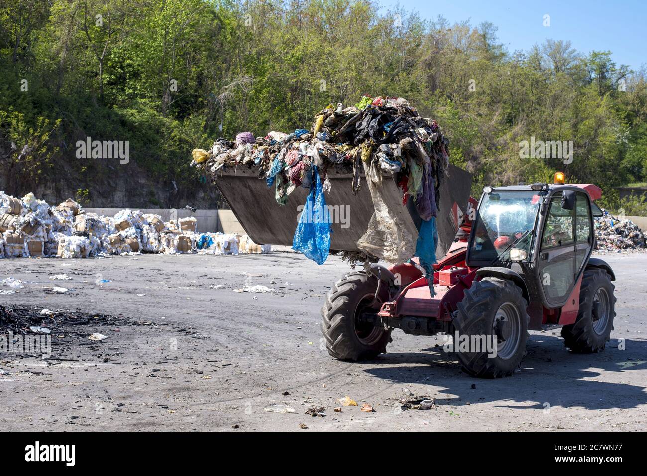 Pala gommata che trasporta i rifiuti urbani all'impianto di trattamento dei rifiuti Foto Stock