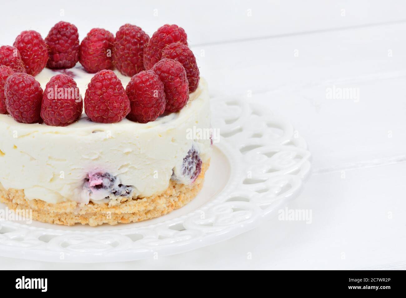 Cheesecake mini con cioccolato bianco e lamponi su tavolo di legno Foto Stock